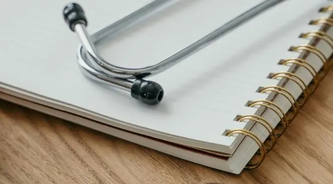 Fonendoscopio sobre un cuaderno y medicamentos